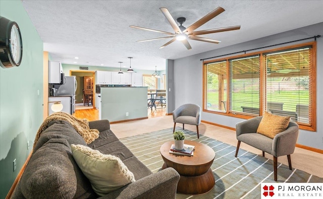 living area with baseboards, light carpet, a ceiling fan, and a textured ceiling