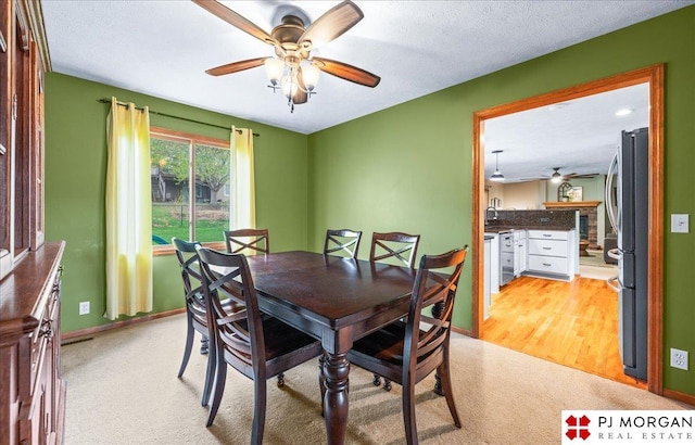 dining space featuring baseboards, a ceiling fan, and light colored carpet