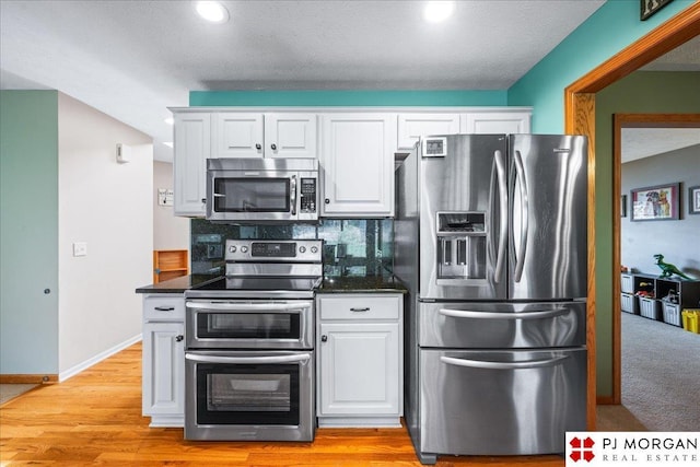 kitchen with recessed lighting, backsplash, white cabinets, and appliances with stainless steel finishes