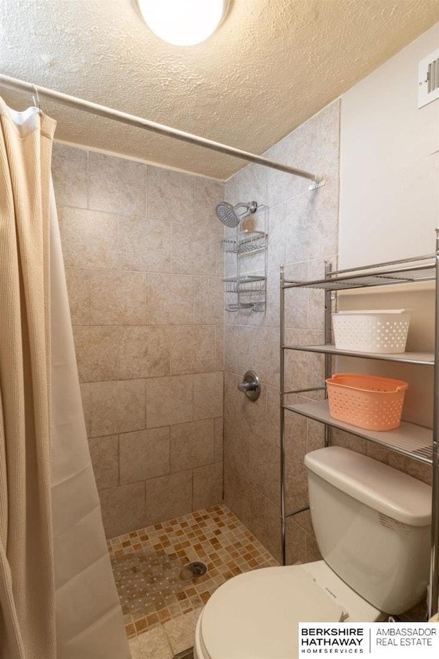 bathroom with toilet, a stall shower, a textured ceiling, and visible vents