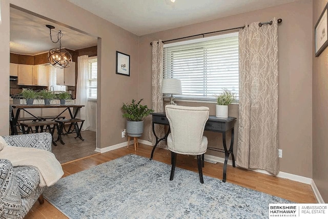 home office with wood finished floors, a chandelier, and baseboards