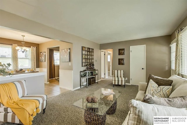 living area featuring a chandelier, baseboards, light colored carpet, and light tile patterned floors