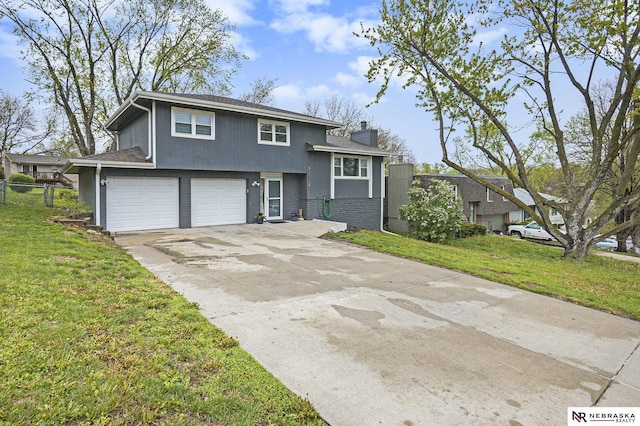 split level home with a chimney, fence, driveway, a front lawn, and an attached garage