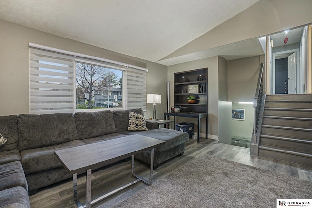 living room featuring stairs, built in features, vaulted ceiling, and wood finished floors