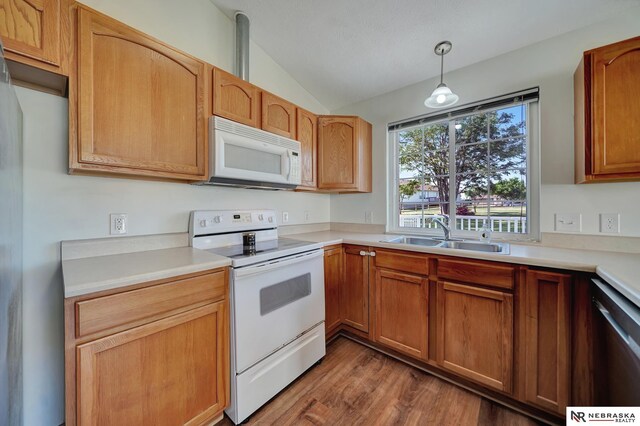 1521 Morton St, Lincoln, NE 68521 - kitchen with white appliances, a sink, vaulted ceiling, wood finished floors, and light countertops