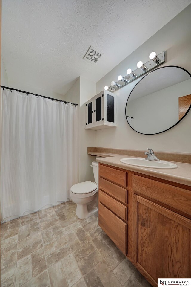 1521 Morton St, Lincoln, NE 68521 - full bath with toilet, vanity, stone finish flooring, a textured ceiling, and a shower with shower curtain