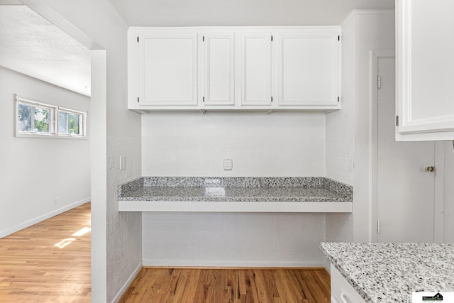 1500 Burnham St, Lincoln, NE 68502 - kitchen featuring light wood-style flooring, white cabinets, baseboards, and light stone countertops