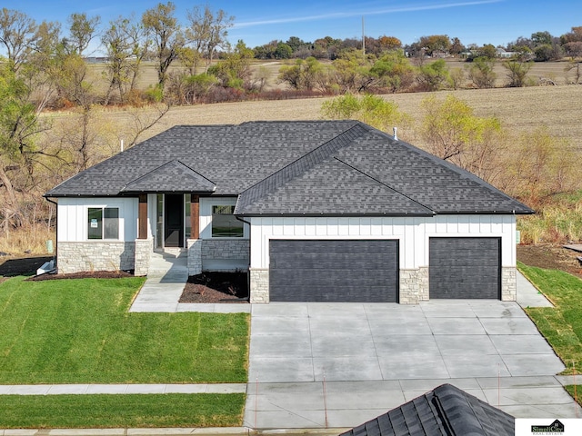 view of front of house featuring a front yard, a shingled roof, a garage, driveway, and stone siding
