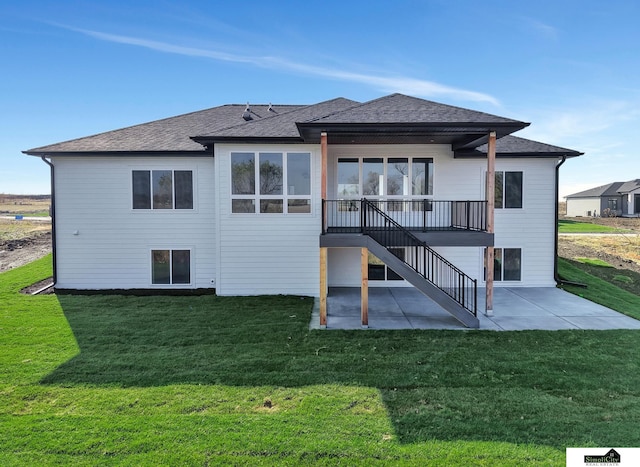 back of property with a lawn, stairway, roof with shingles, and a patio area