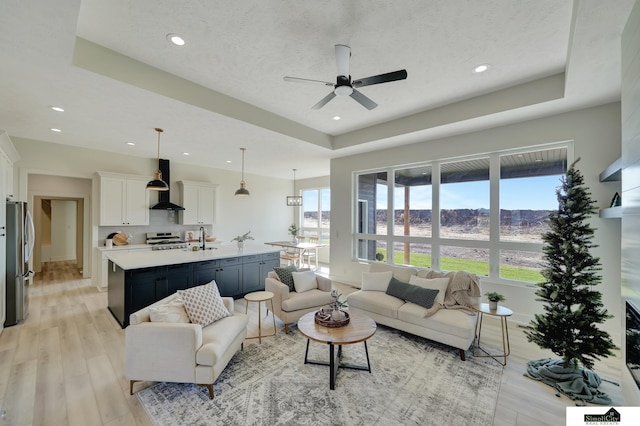 living area featuring light wood finished floors, a ceiling fan, recessed lighting, and a wealth of natural light