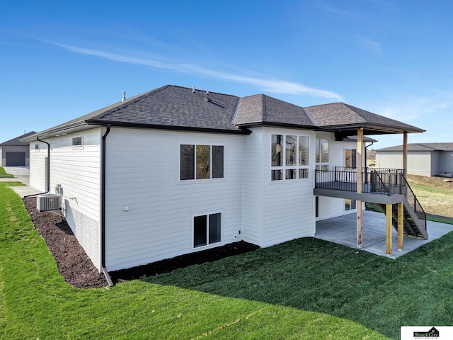 back of property featuring a deck, a patio area, roof with shingles, stairway, and a yard