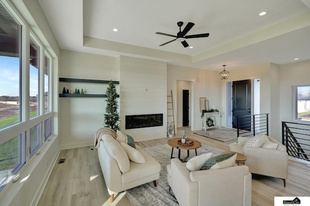 living area featuring recessed lighting, a tray ceiling, light wood-type flooring, a ceiling fan, and visible vents