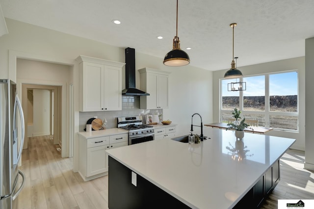 kitchen with a sink, stainless steel appliances, recessed lighting, wall chimney exhaust hood, and backsplash