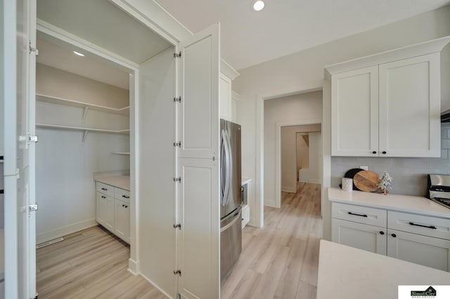 kitchen featuring white cabinetry, light wood-type flooring, and freestanding refrigerator