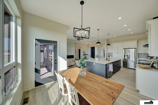 kitchen with appliances with stainless steel finishes, light countertops, light wood-style flooring, and a sink