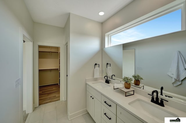 bathroom featuring tile patterned floors, a spacious closet, double vanity, and a sink