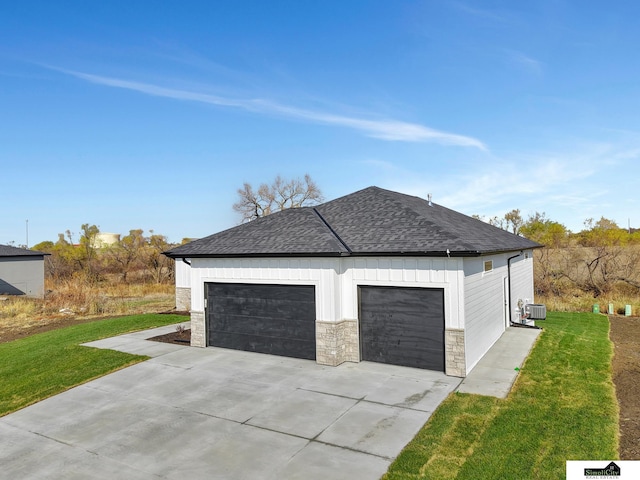 view of side of home featuring concrete driveway, roof with shingles, an attached garage, a lawn, and central AC