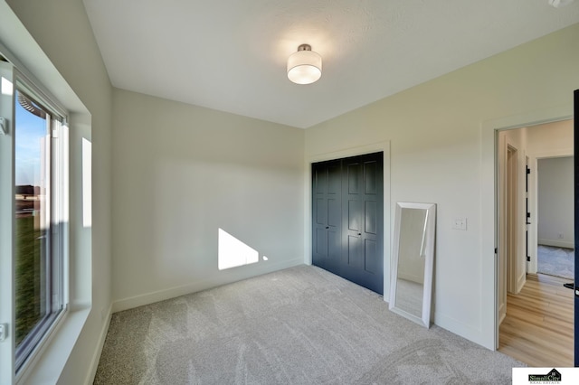 unfurnished bedroom featuring a closet, light carpet, and baseboards