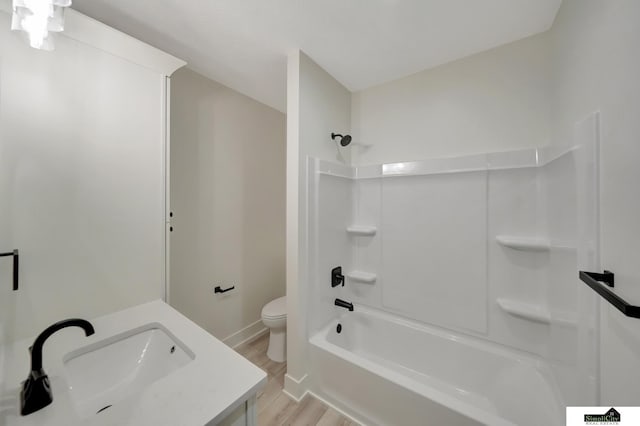 bathroom featuring wood finished floors,  shower combination, toilet, vanity, and baseboards