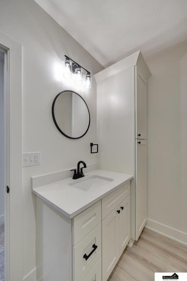 bathroom with baseboards, wood finished floors, and vanity