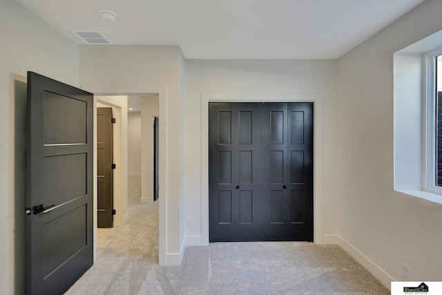 unfurnished bedroom with a closet, visible vents, carpet, and baseboards
