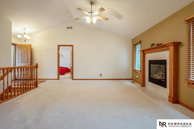unfurnished living room with light colored carpet, a chandelier, vaulted ceiling, a tile fireplace, and a ceiling fan
