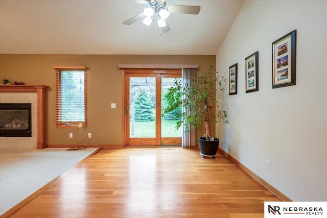 doorway with wood finished floors, healthy amount of natural light, ceiling fan, and baseboards