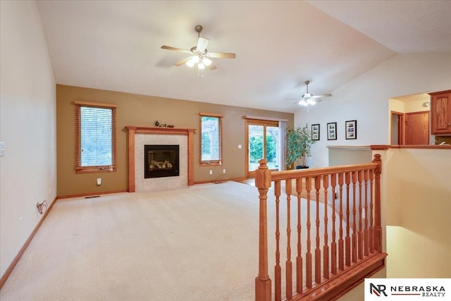 living room with vaulted ceiling, ceiling fan, baseboards, and a fireplace with flush hearth