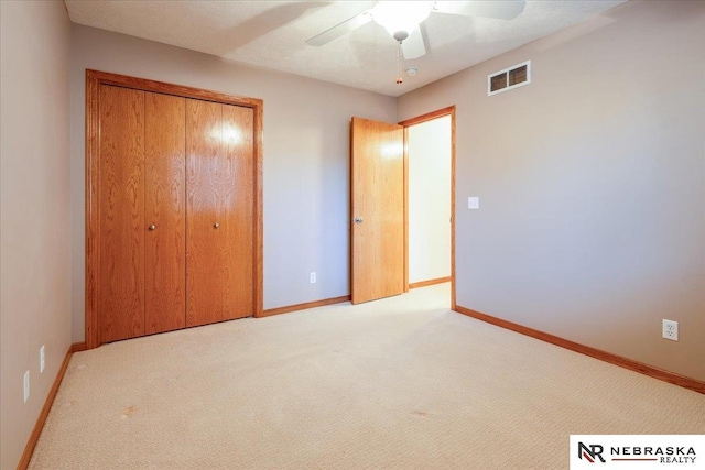 unfurnished bedroom featuring a closet, light colored carpet, baseboards, and ceiling fan