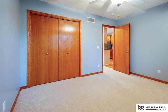 unfurnished bedroom featuring baseboards, a closet, carpet floors, and ceiling fan