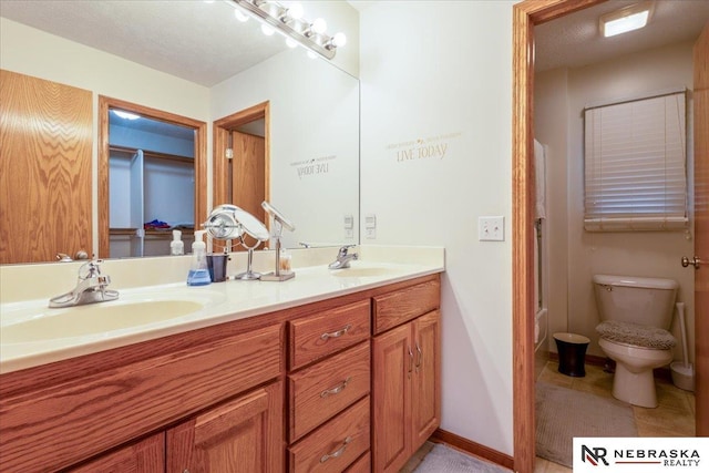 full bathroom with double vanity, toilet, and baseboards