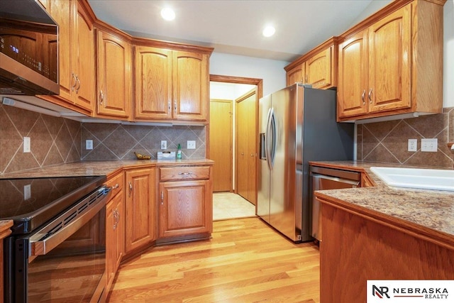 kitchen featuring appliances with stainless steel finishes, a sink, light wood-type flooring, decorative backsplash, and recessed lighting