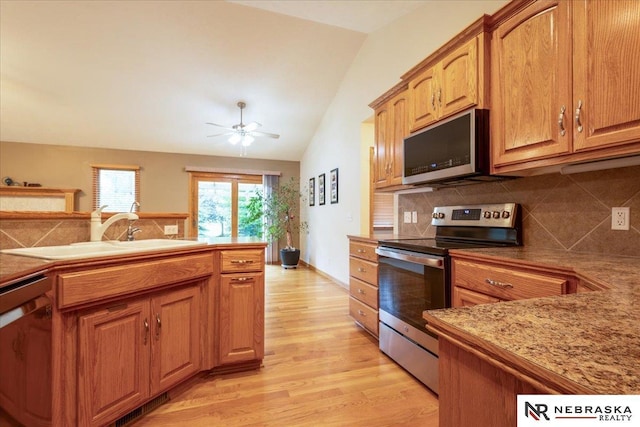 kitchen with appliances with stainless steel finishes, a sink, lofted ceiling, a ceiling fan, and backsplash