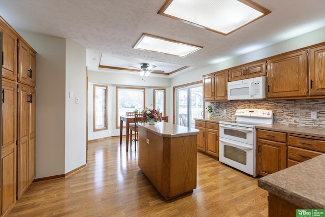 kitchen with tasteful backsplash, white appliances, brown cabinetry, and a kitchen island