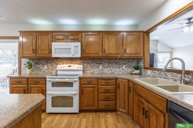 kitchen featuring a sink, brown cabinetry, and white appliances