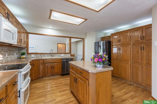 kitchen featuring light wood-style floors, stainless steel appliances, brown cabinetry, and a sink