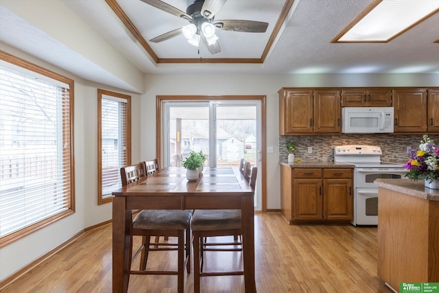 kitchen featuring ceiling fan, light wood-style floors, baseboards, white appliances, and brown cabinetry