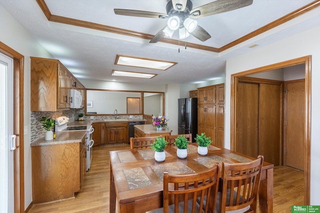 dining room featuring crown molding, ceiling fan, a raised ceiling, and light wood-type flooring