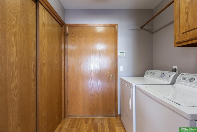 laundry area featuring washer and dryer, light wood-type flooring, and cabinet space