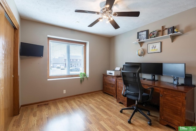 office space with light wood finished floors, baseboards, visible vents, a ceiling fan, and a textured ceiling