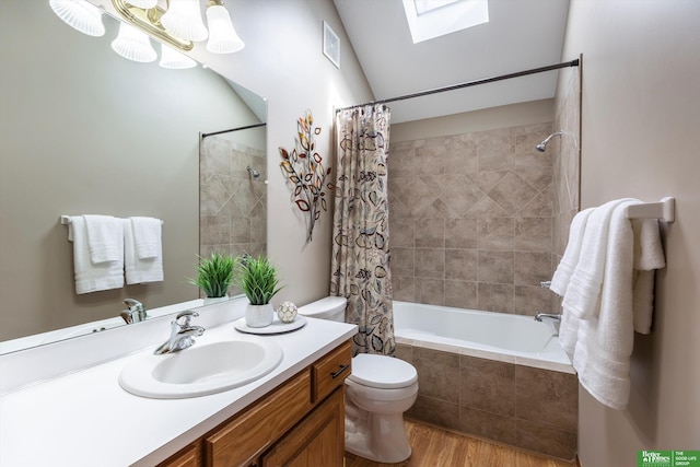 full bathroom with a skylight, wood finished floors, tiled shower / bath, toilet, and vanity