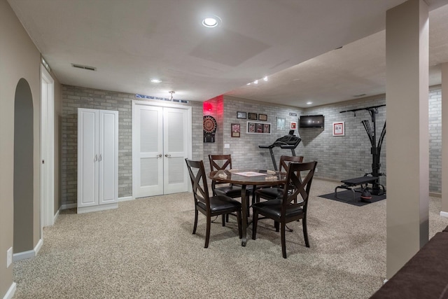 carpeted dining area featuring baseboards, visible vents, arched walkways, and recessed lighting