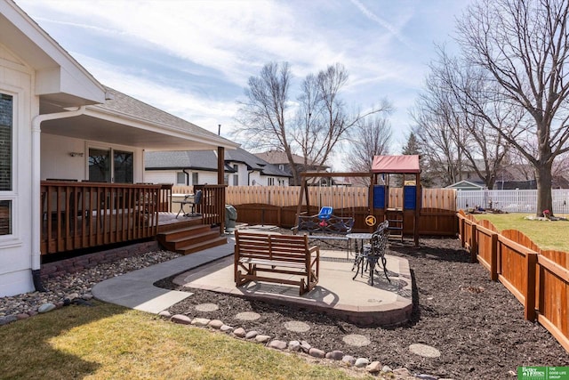 view of yard with a fenced backyard, a wooden deck, a playground, and a patio area