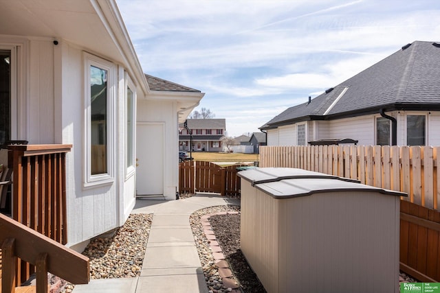 view of home's exterior featuring fence, a shingled roof, and a residential view