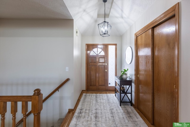 foyer featuring wood finished floors, an inviting chandelier, vaulted ceiling, baseboards, and a textured ceiling
