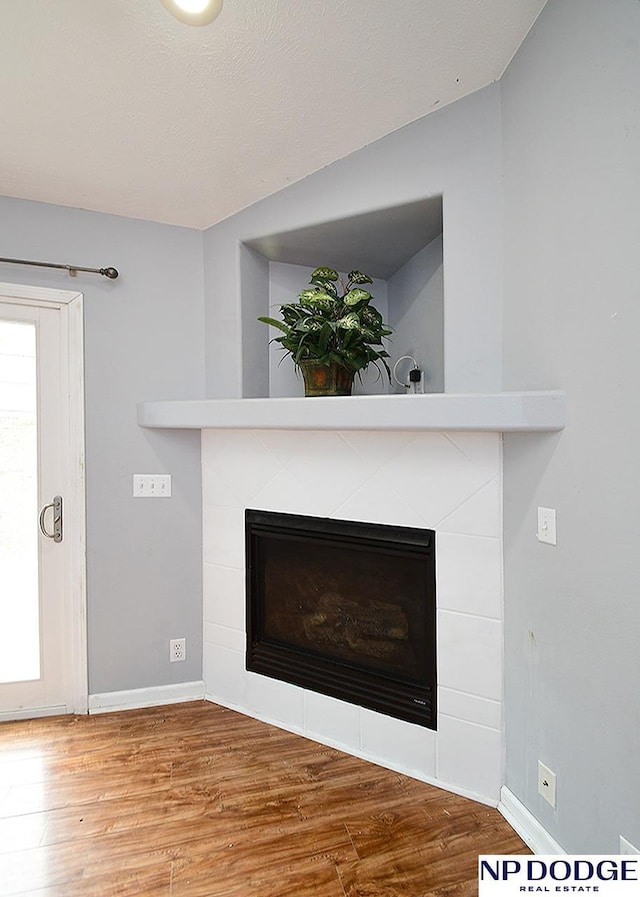 room details featuring baseboards, wood finished floors, and a fireplace