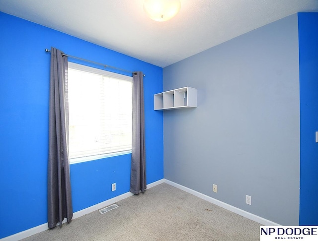 spare room featuring visible vents, carpet, and baseboards