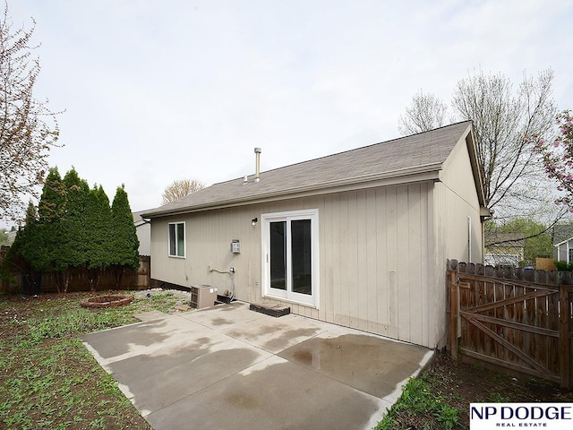 rear view of house with a patio, fence, and roof with shingles