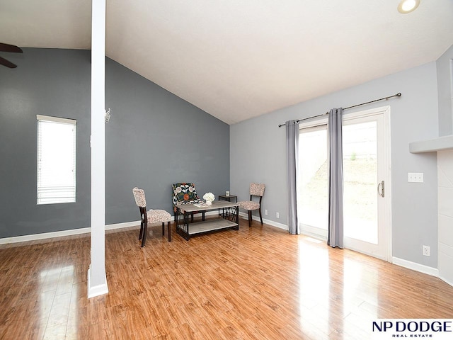 living area with lofted ceiling, ceiling fan, light wood finished floors, and baseboards