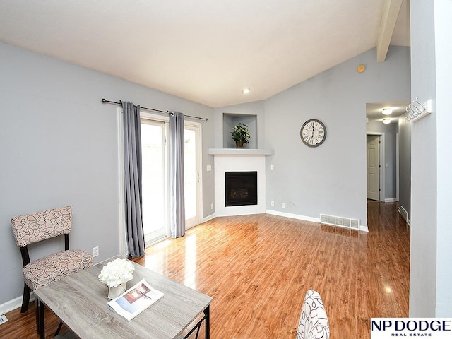 living area with visible vents, lofted ceiling with beams, baseboards, a fireplace, and wood finished floors